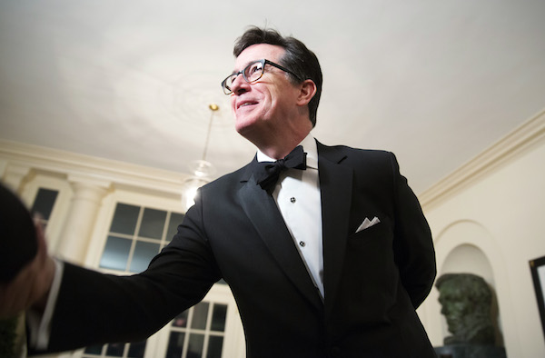 Comedian Stephen Colbert greets a reporter as he arrives for the State Dinner being held for French President Francois Hollande at the White House