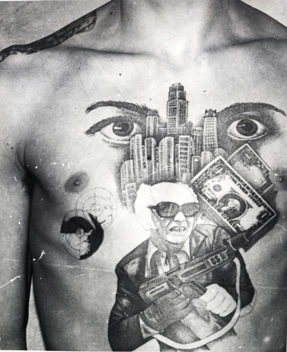 The dollar bills, skyscrapers and machine gun with the initials ‘US’ stamped on it convey this inmate’s love for the American mafia-like lifestyle. The eyes signify ‘I’m watching over you’ (the other inmates in the prison or camp). The epaulette tattooed on the shoulder denotes the inmates 'rank' among the criminal caste.