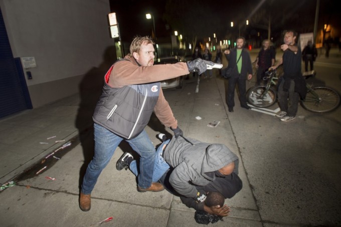 An undercover police officer, who had been marching with anti-police demonstrators, aims his gun at protesters. REUTERS/Noah Berger
