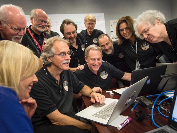 In the Mission Control center, NASA's New Horizons operations team celebrates a successful visit to Pluto by the space probe.